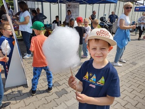 policjanci bawią się z dziećmi w tle teren zewnętrzny jednostki, radiowozy, banery, dzieci i dorośli