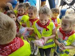 policjanci bawią się z dziećmi w tle teren zewnętrzny jednostki, radiowozy, banery, dzieci i dorośli