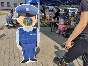 policjanci bawią się z dziećmi w tle teren zewnętrzny jednostki, radiowozy, banery, dzieci i dorośli