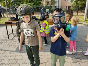 policjanci bawią się z dziećmi w tle teren zewnętrzny jednostki, radiowozy, banery, dzieci i dorośli