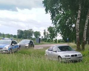 pojazd BMW stojący w trawie w tle radiowóz i pojazd cywilny
