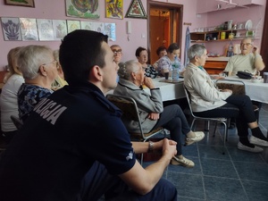 policjanci rozmawiają z seniorami w tle pomieszczenie