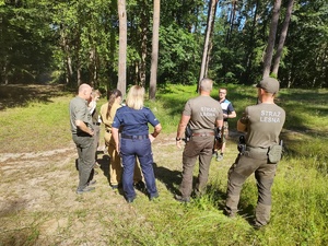 służby kontrolują obóz w tle teren leśny