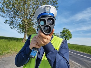 policjant mierzy prędkość w tle ulica