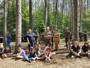służby rozmawiają z harcerzami w tle las