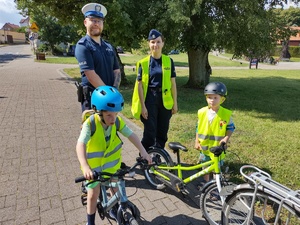 policjanci wręczają rowerzystom odblaski w tle promenada jeziora
