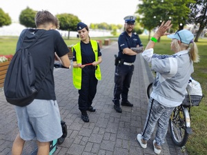 policjanci wręczają odblaski w tle promenada jeziora