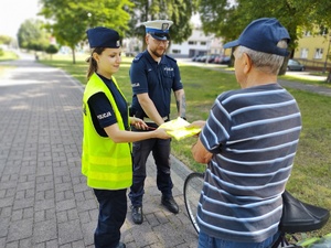 policjanci wręczają odblaski w tle promenada jeziora