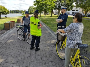 policjanci wręczają odblaski w tle promenada jeziora
