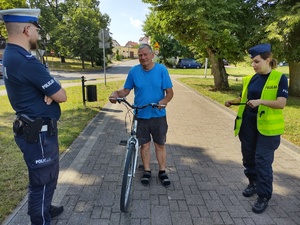 policjanci wręczają odblaski w tle promenada jeziora