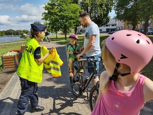 policjanci wręczają odblaski w tle promenada jeziora