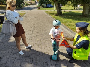 policjanci wręczają odblaski w tle promenada jeziora