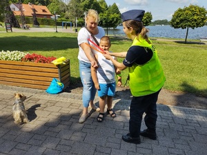 policjanci wręczają odblaski w tle promenada jeziora