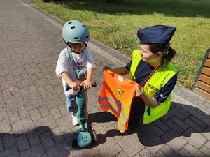 policjanci wręczają odblaski w tle promenada jeziora