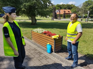 policjanci wręczają odblaski w tle promenada jeziora