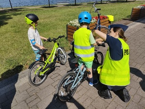 policjanci wręczają odblaski w tle promenada jeziora