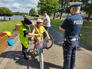 policjanci wręczają odblaski w tle promenada jeziora
