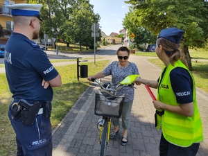 policjanci wręczają odblaski w tle promenada jeziora