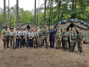 policjanci rozmawiają z harcerzami i zuchami w tle las i namioty
