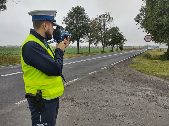 policjant sprawdza prędkość pojazdów w tle ulica