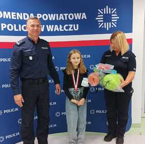 Komendant wręcza nagrody uczestnikom konkursu w tle baner