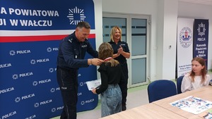 Komendant wręcza nagrody uczestnikom konkursu w tle baner