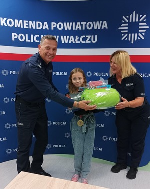 Komendant wręcza nagrody uczestnikom konkursu w tle baner