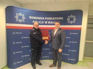 komendant i burmistrz podczas wręczenia podziękowań w tle baner z logo policji