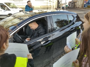 policjant prowadzi działania z uczniami w tle ulica i pojazdy