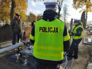 policjanci wręczają odblaski osobom odwiedzającym cmentarze
