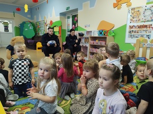 policjanci rozmawiają z przedszkolakami w tle sala