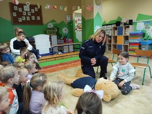 policjanci rozmawiają z przedszkolakami w tle sala