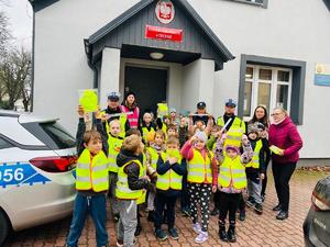 Policjanci przed posterunkiem z uczniami. W tle ulica