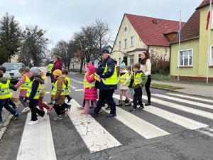 Policjanci przed posterunkiem z uczniami. W tle ulica