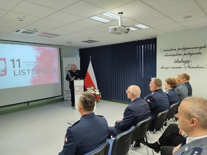 Policjanci na uroczystej zbiórce w tle banery i flaga Polski