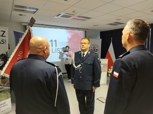 Policjanci na uroczystej zbiórce w tle banery i flaga Polski