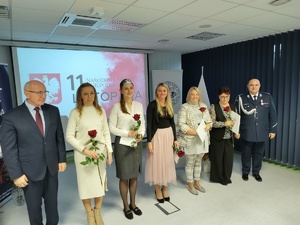 Policjanci na uroczystej zbiórce w tle banery i flaga Polski