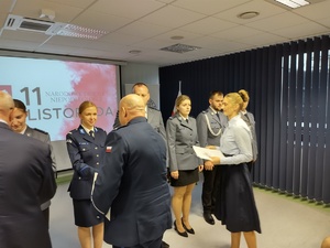 Policjanci na uroczystej zbiórce w tle banery i flaga Polski