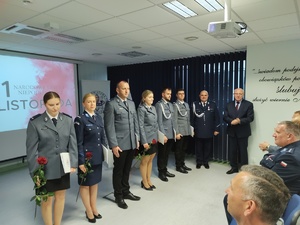 Policjanci na uroczystej zbiórce w tle banery i flaga Polski