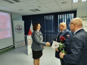 Policjanci na uroczystej zbiórce w tle banery i flaga Polski