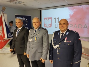 Policjanci na uroczystej zbiórce w tle banery i flaga Polski