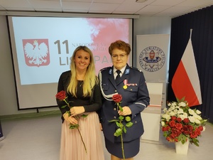 Policjanci na uroczystej zbiórce w tle banery i flaga Polski