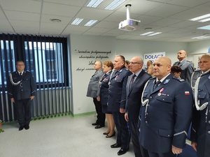 Policjanci na uroczystej zbiórce w tle banery i flaga Polski