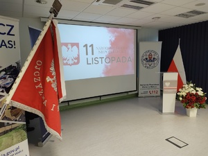 Policjanci na uroczystej zbiórce w tle banery i flaga Polski