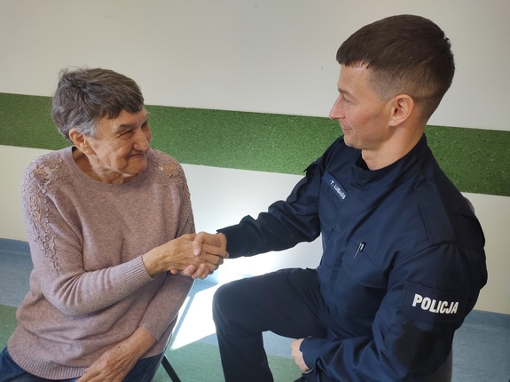 policjant ściska dłoń starszej kobiety