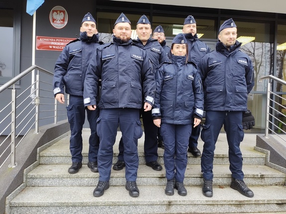 policjanci pozują do zdjęcia w tle budynek komendy