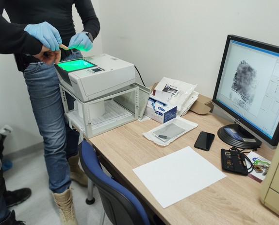 policjant ściąga ślady linii papilarnych od sprawcy