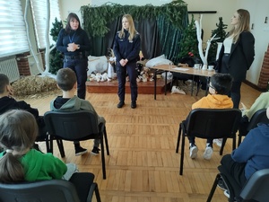 Policjantki i pracownik sanepidu rozmawiają z uczniami w tle sala lekcyjna