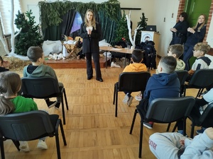 Policjantki i pracownik sanepidu rozmawiają z uczniami w tle sala lekcyjna