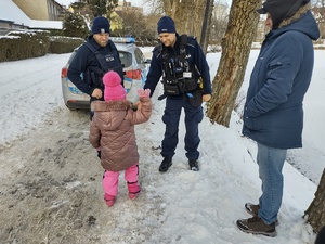 policjanci witają się dziewczynką w tle radiowóz